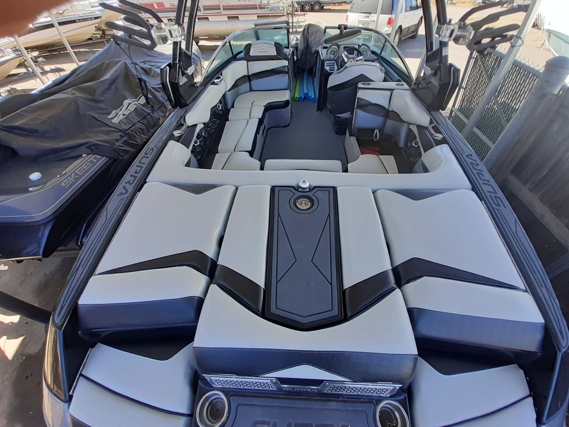 Top view of a sleek black-and-gray speedboat with padded seats docked in a marina