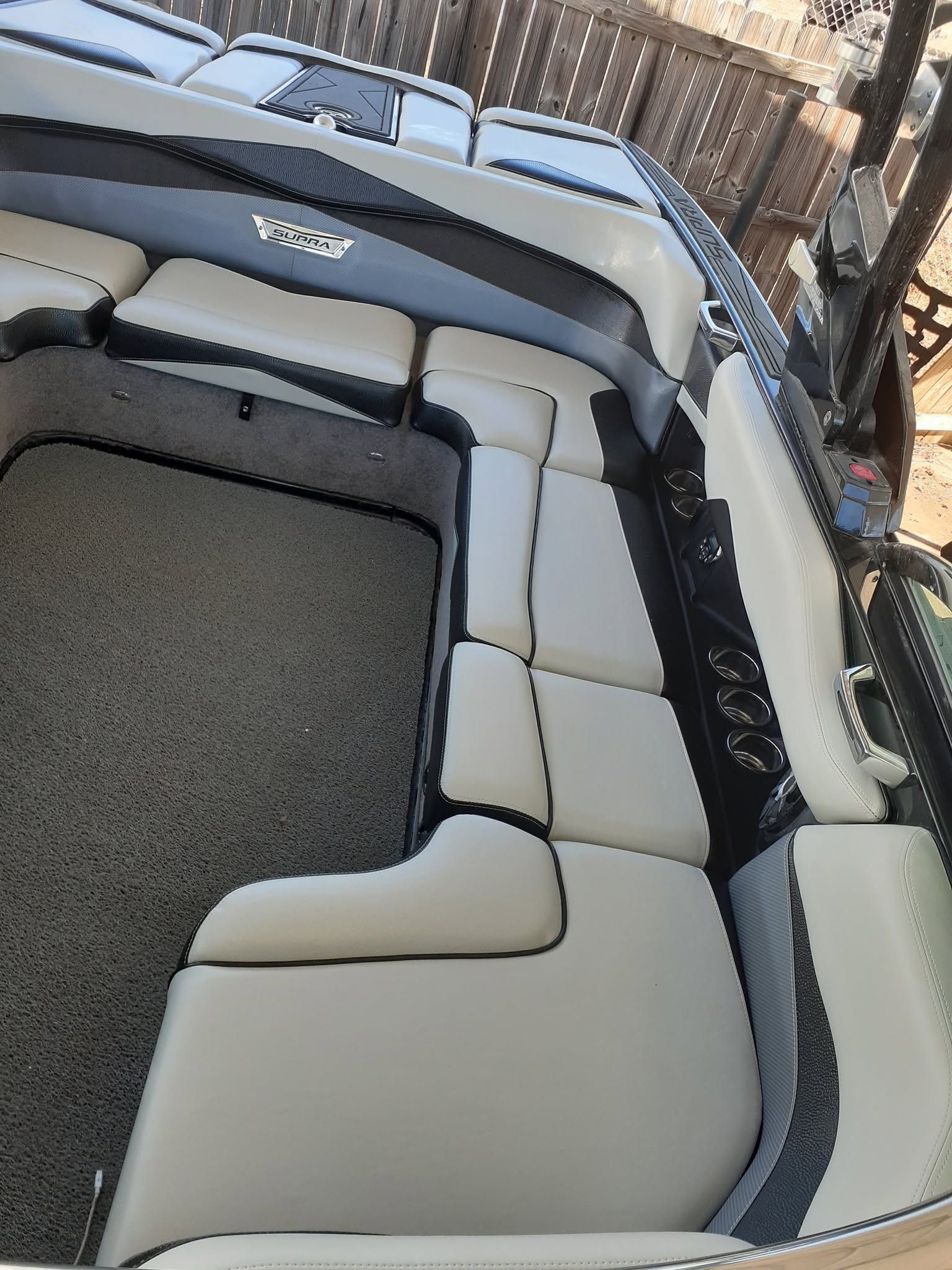 Gray-and-white boat interior with cushioned seating and carpeted floor outdoors
