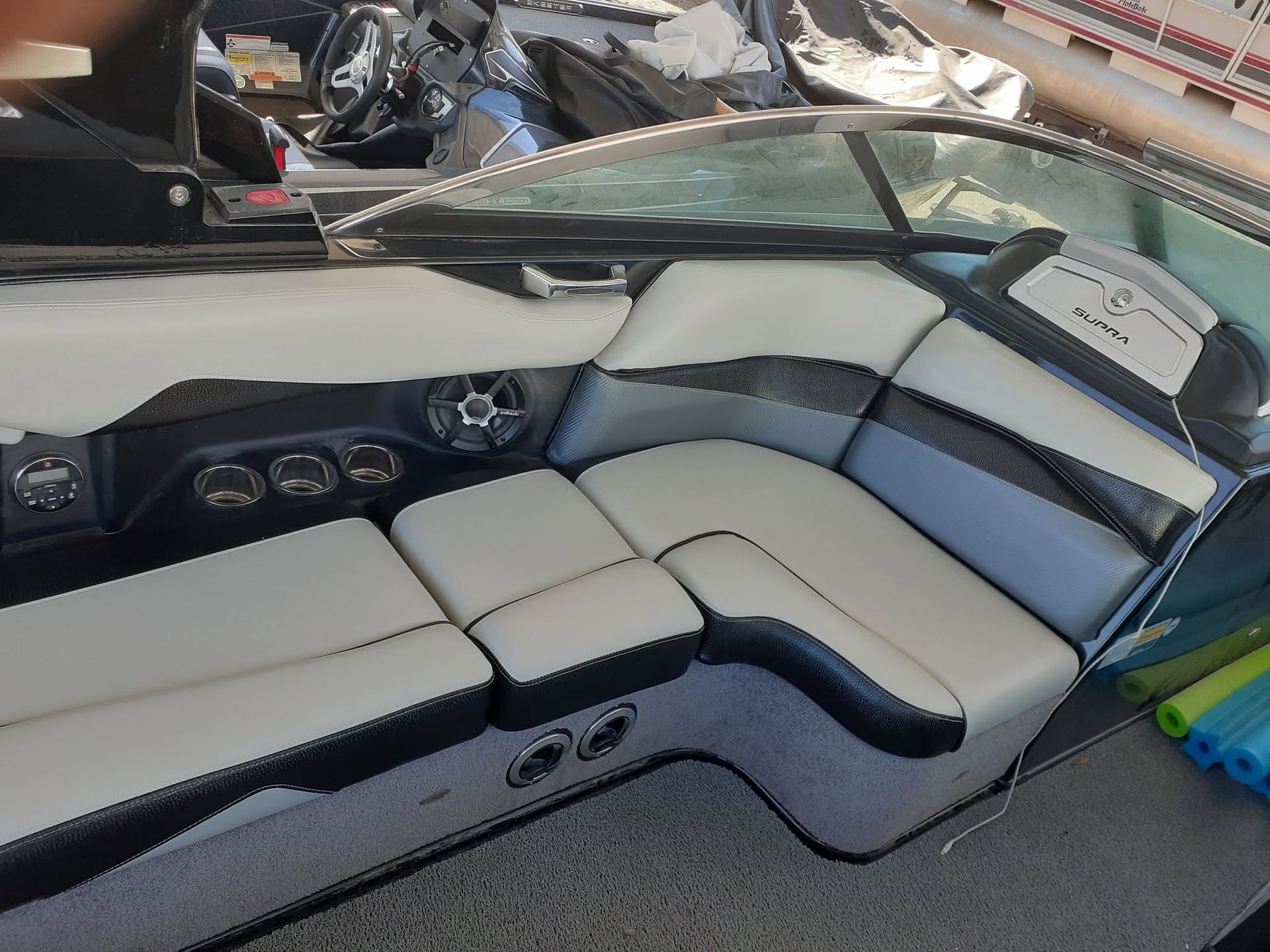 Boat cockpit with beige cushioned seating, dark dashboard gauges, and a windshield panel