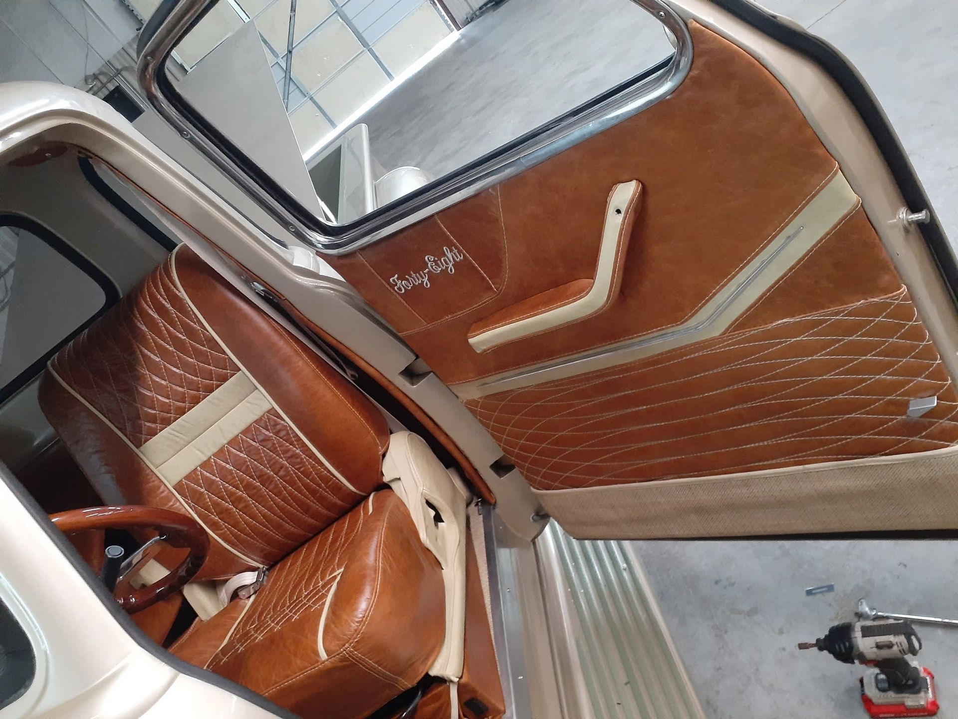 Open car door with brown quilted interior trim and leather seats inside a vehicle.