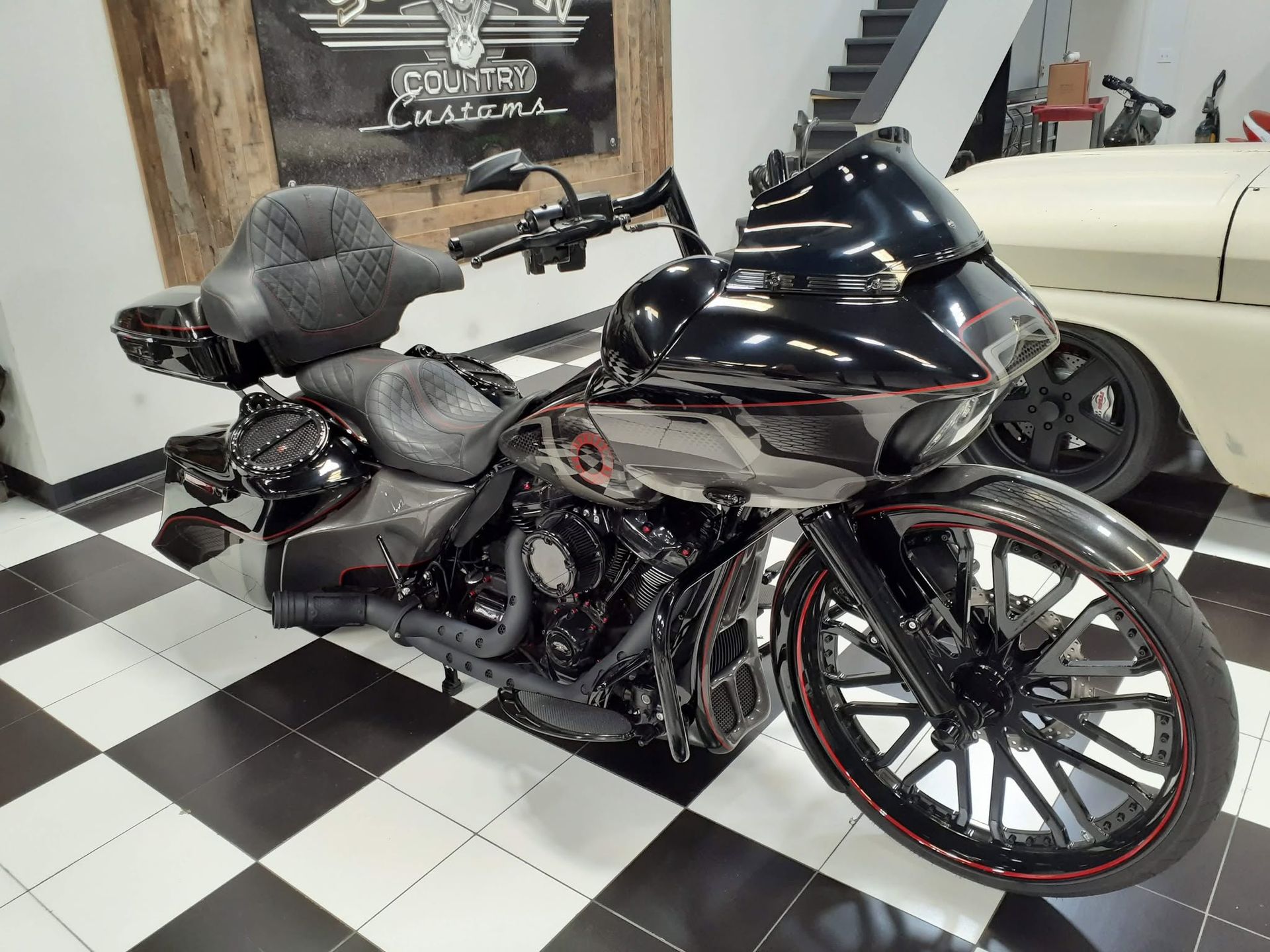 Custom black and chrome motorcycle with red wheel accents on a checkered showroom floor