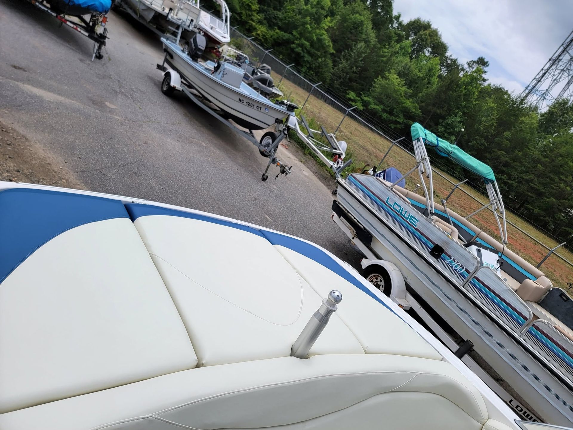 People and boats at a marina, with a blue-and-white boat in the foreground and a docked shoreline behind.