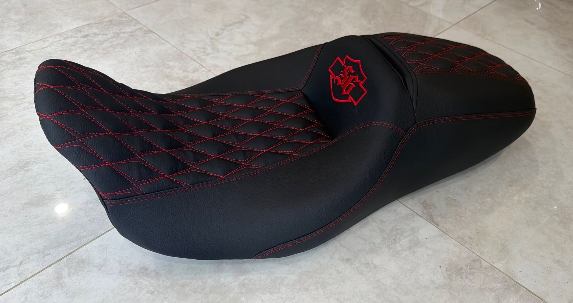 Black and red patterned motorcycle seat on a light floor