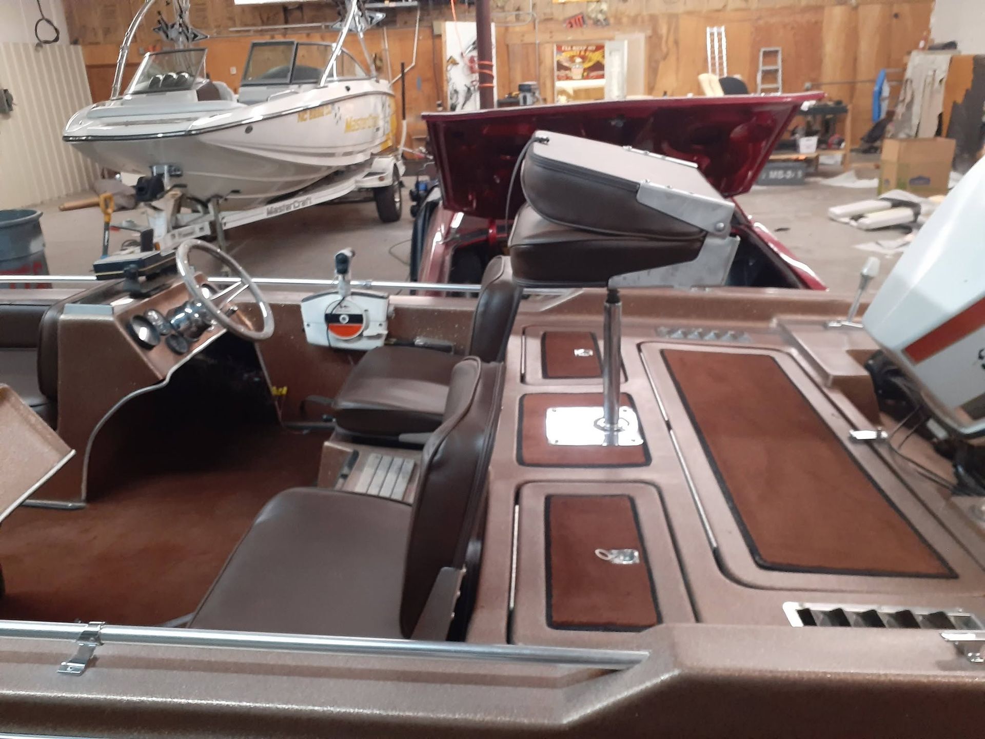 Classic boat cockpit with brown upholstery and steering wheel inside a wooden boathouse