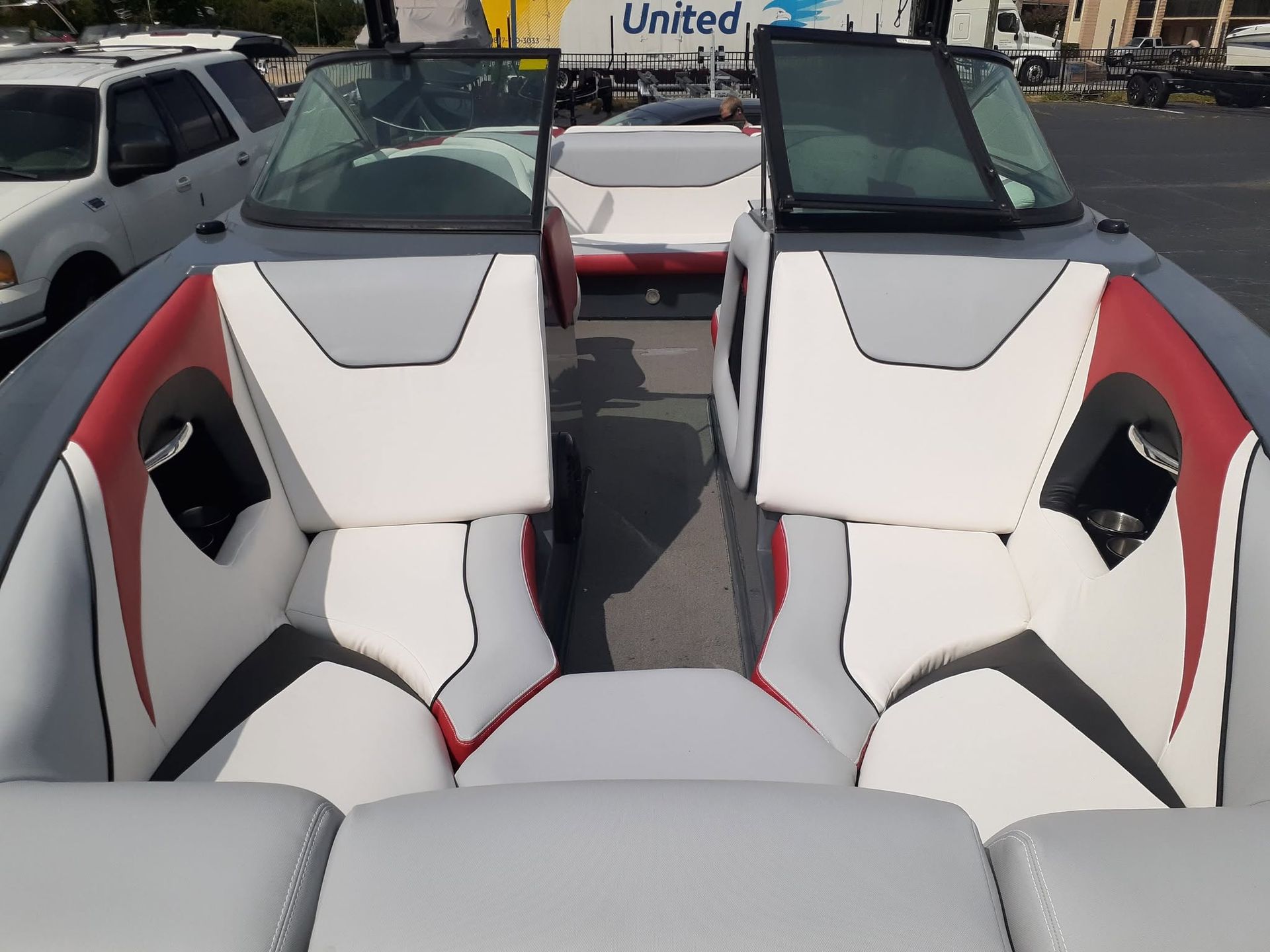 Boat cockpit with white, gray, and red seating, viewed from the stern in a marina