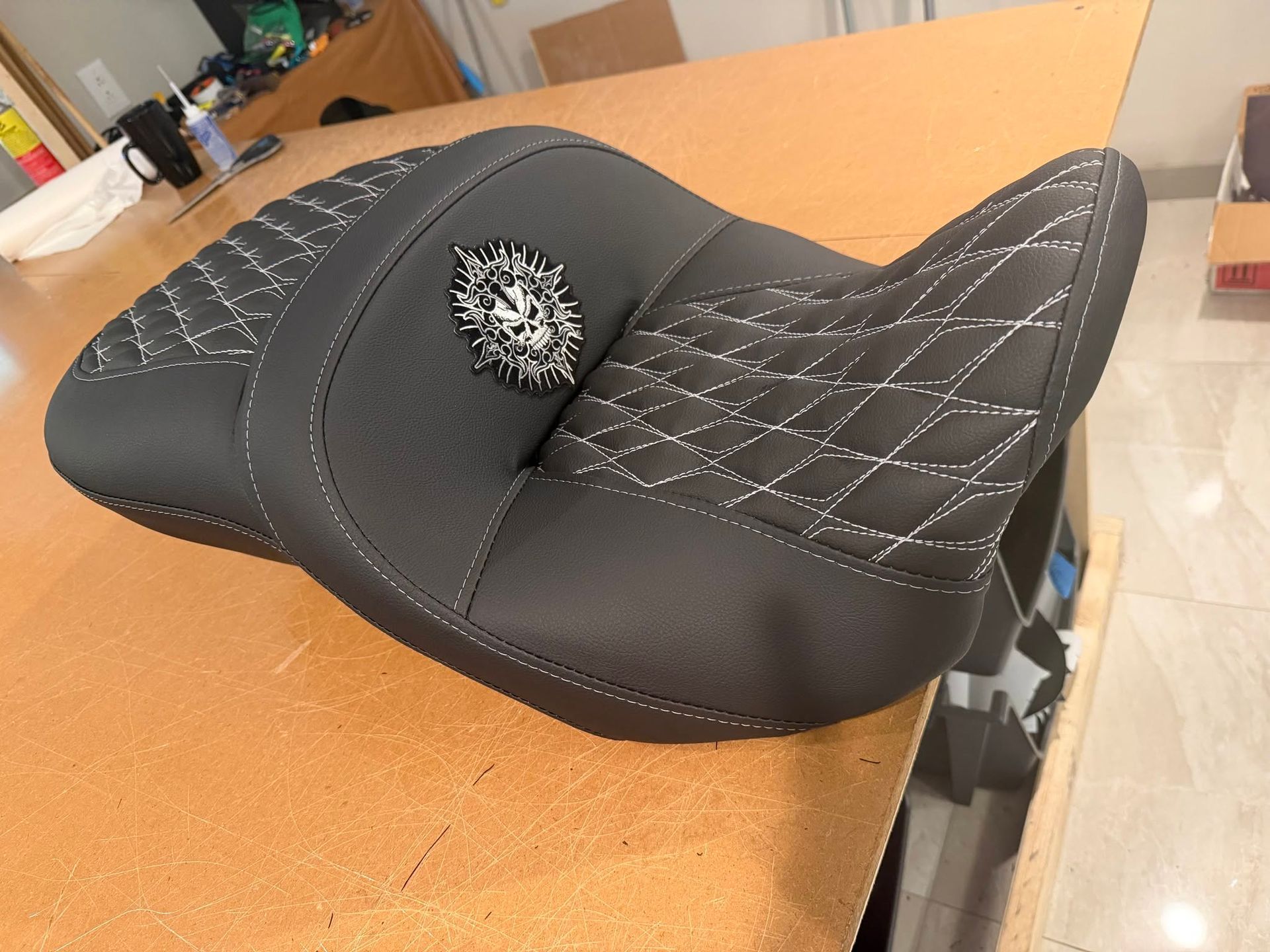 Top-down view of a black motorcycle seat with a gray cushioned backrest.