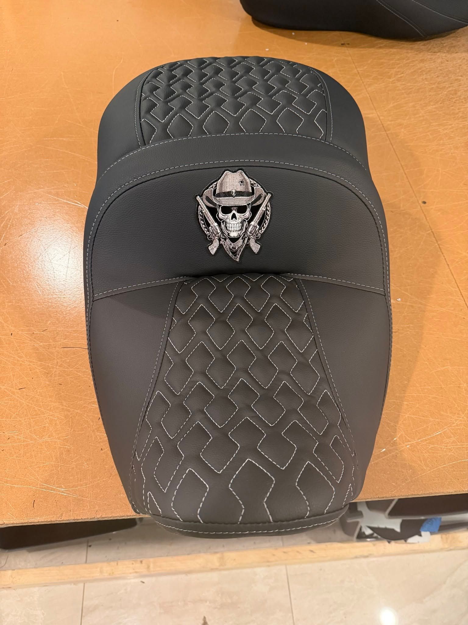 Black textured car seat cover with a small skull emblem on an orange floor