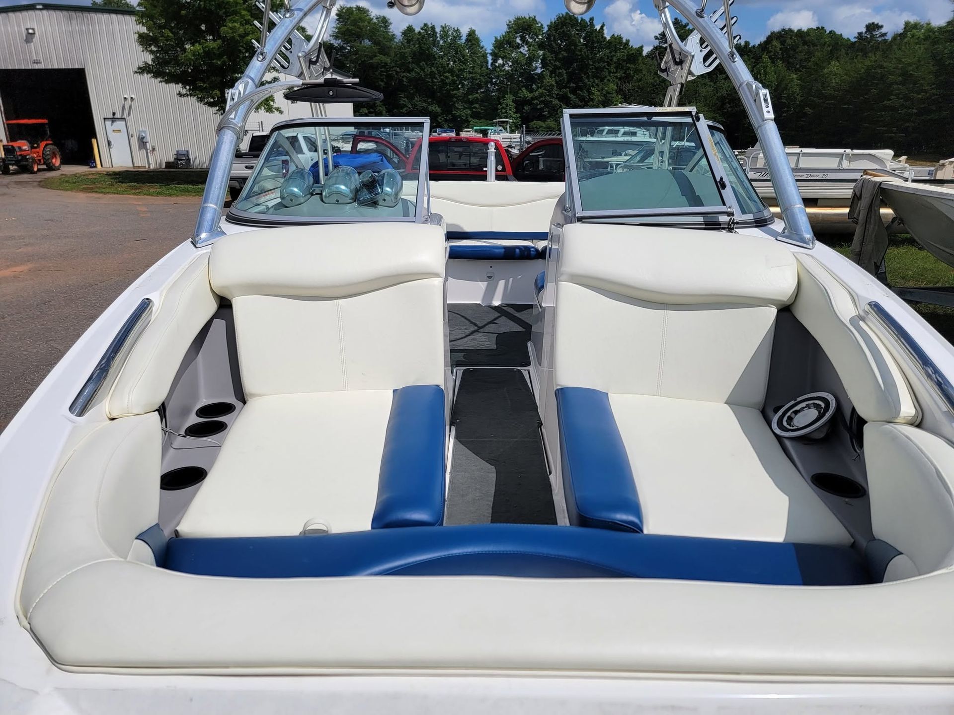 White and blue speedboat interior with twin seats and a wakeboard arch, docked outdoors