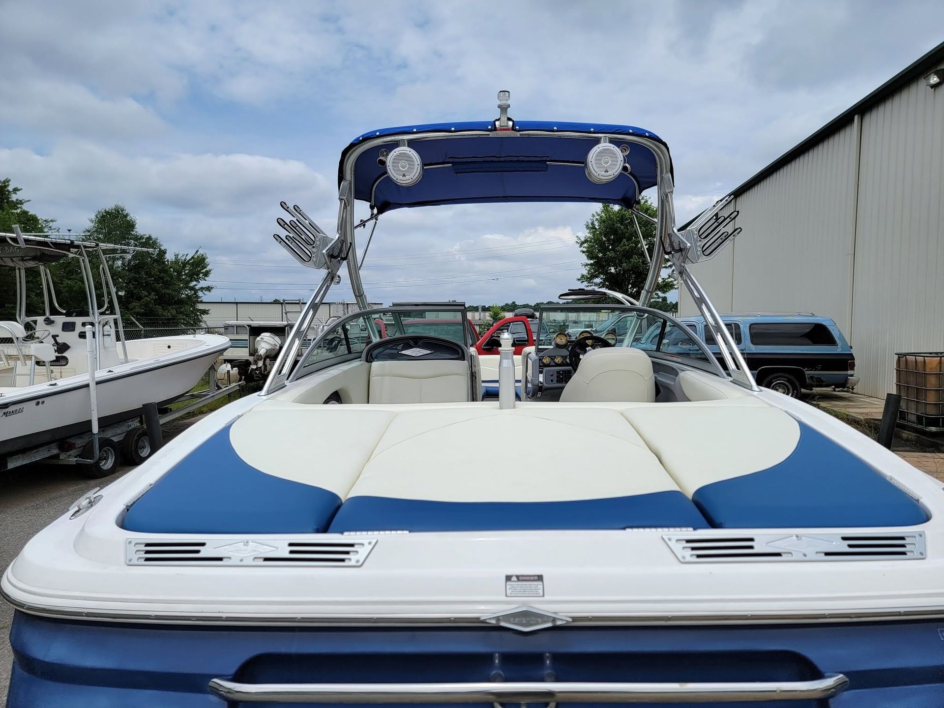 Blue-and-white speedboat docked beside a marina building under a cloudy sky