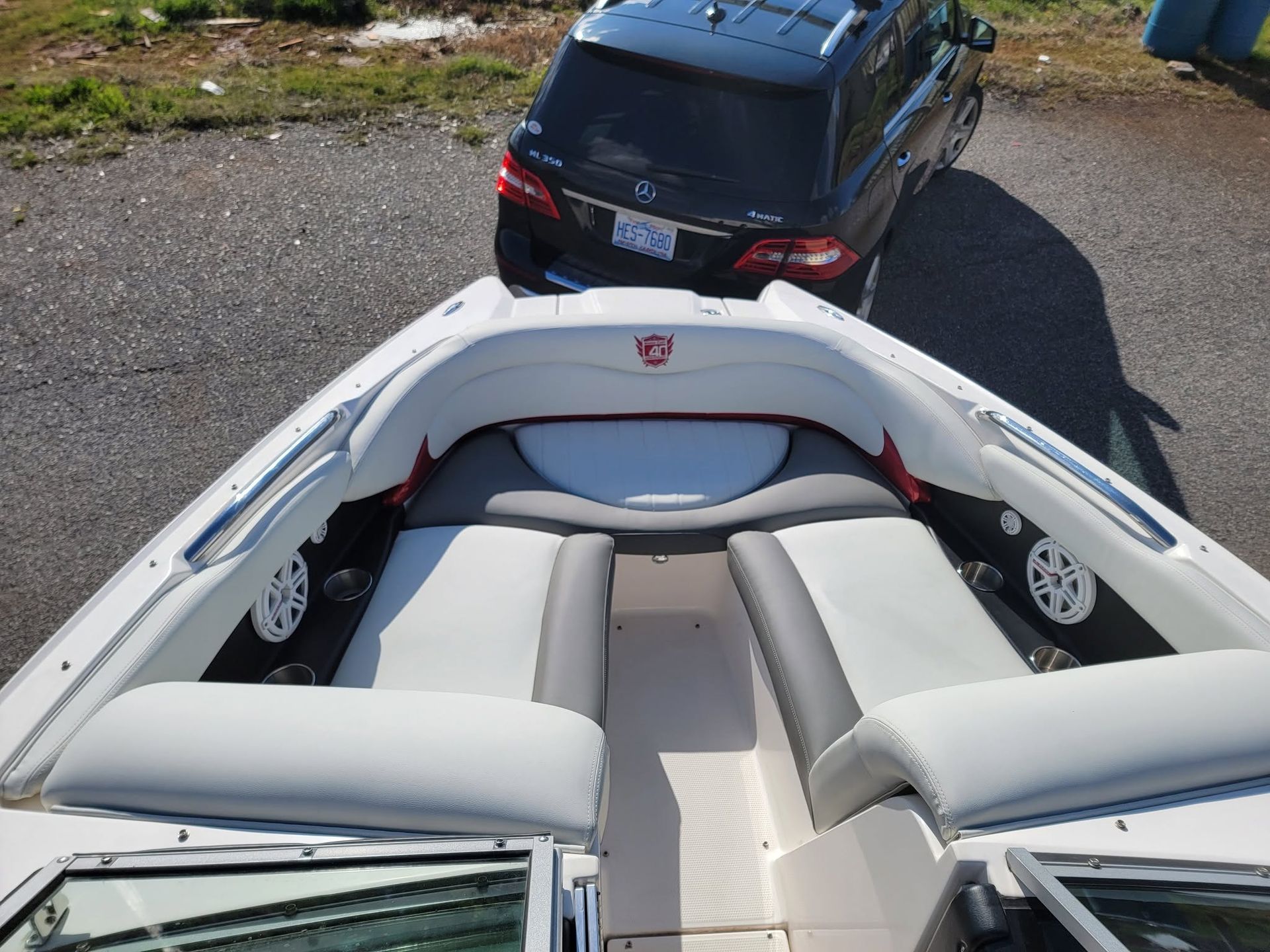 White boat cockpit with gray seats and a black SUV parked ahead on a gravel surface