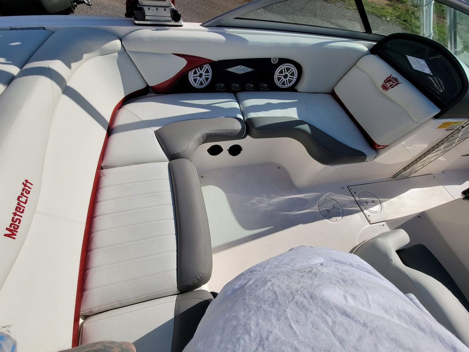 White-and-gray boat cockpit with cushioned seating and steering wheel, viewed from above