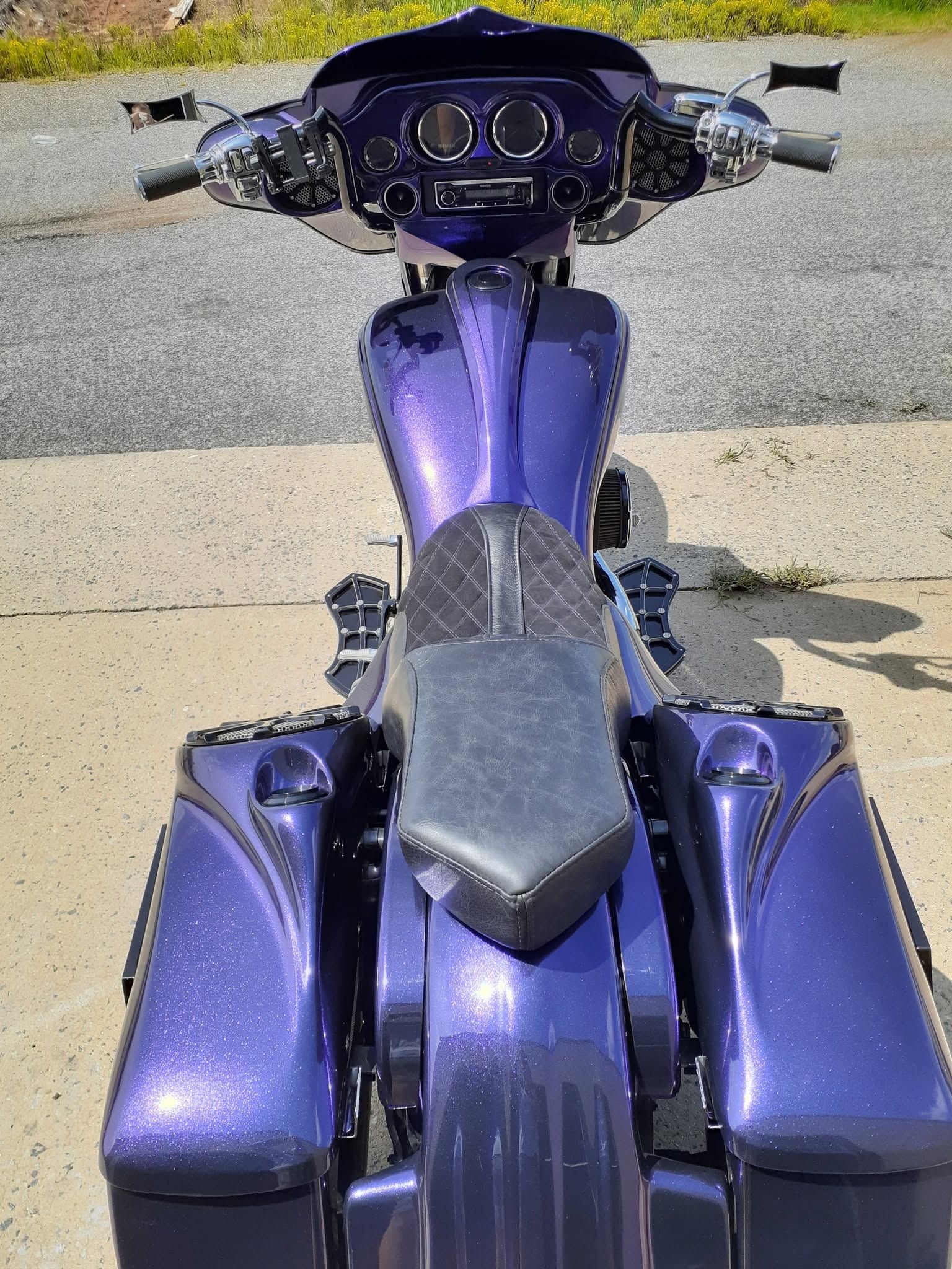 Front view of a metallic purple motorcycle parked on pavement.