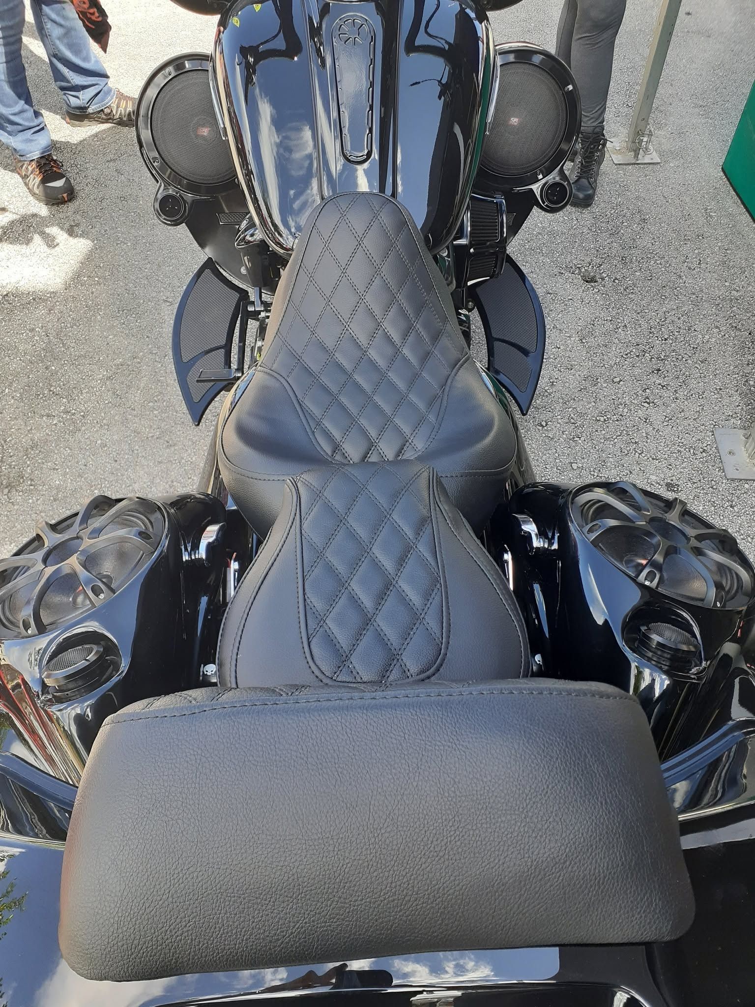 Top-down view of a black motorcycle seat with a gray cushioned backrest.