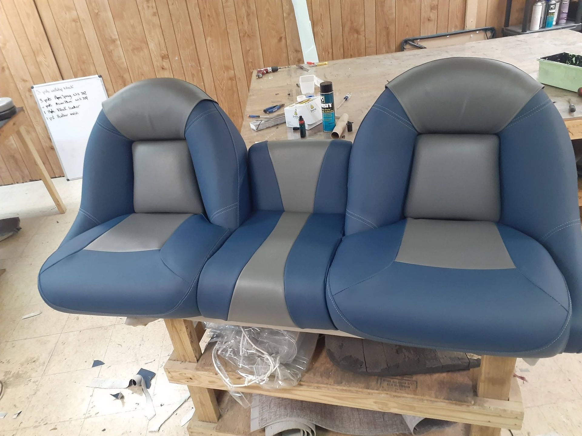 Two blue-and-gray upholstered boat seats on a workshop pallet