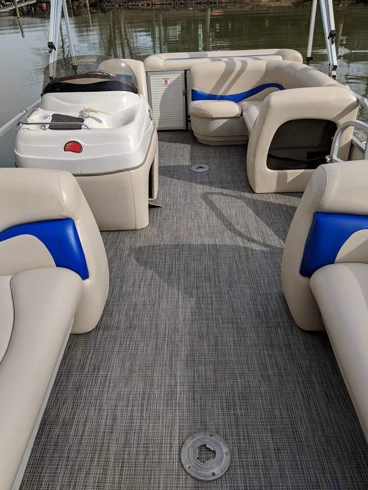 Cream-colored and blue cushioned seating area with gray carpet on a boat or ferry deck.