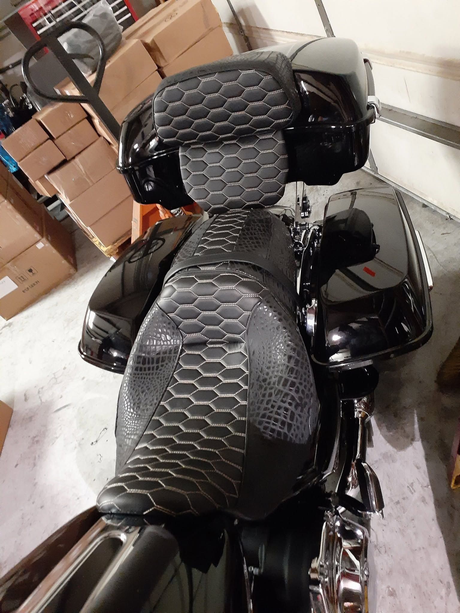Black motorcycle with quilted gray seat and backrest in a garage, viewed from above