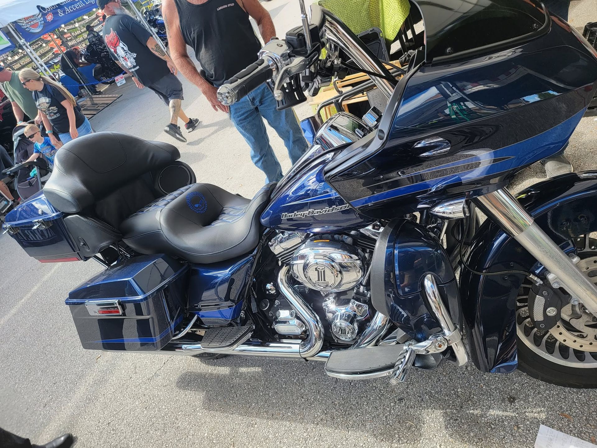 Blue touring motorcycle with chrome details parked at a crowded outdoor event