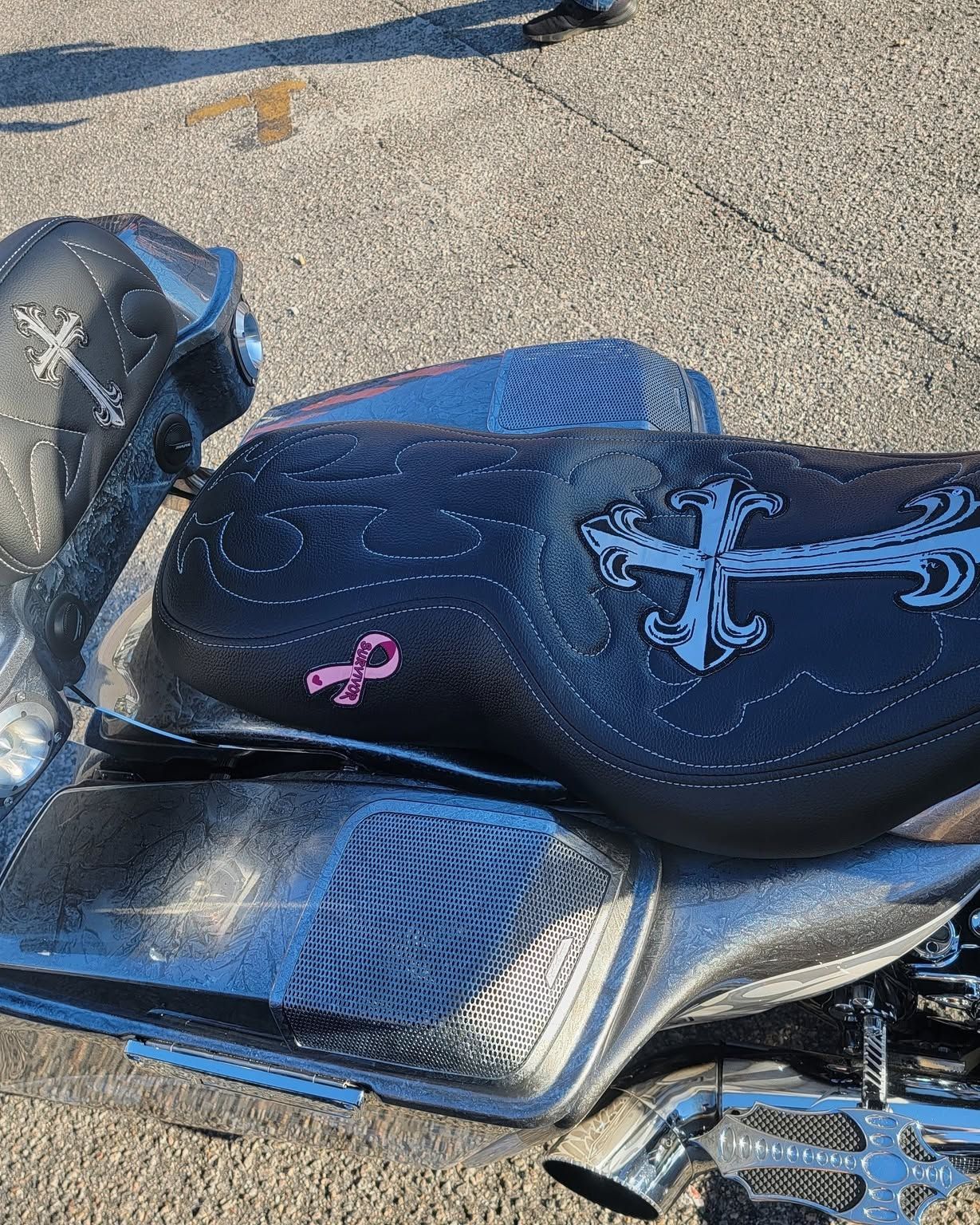 Black and silver motorcycle seat with blue accents on sunlit pavement