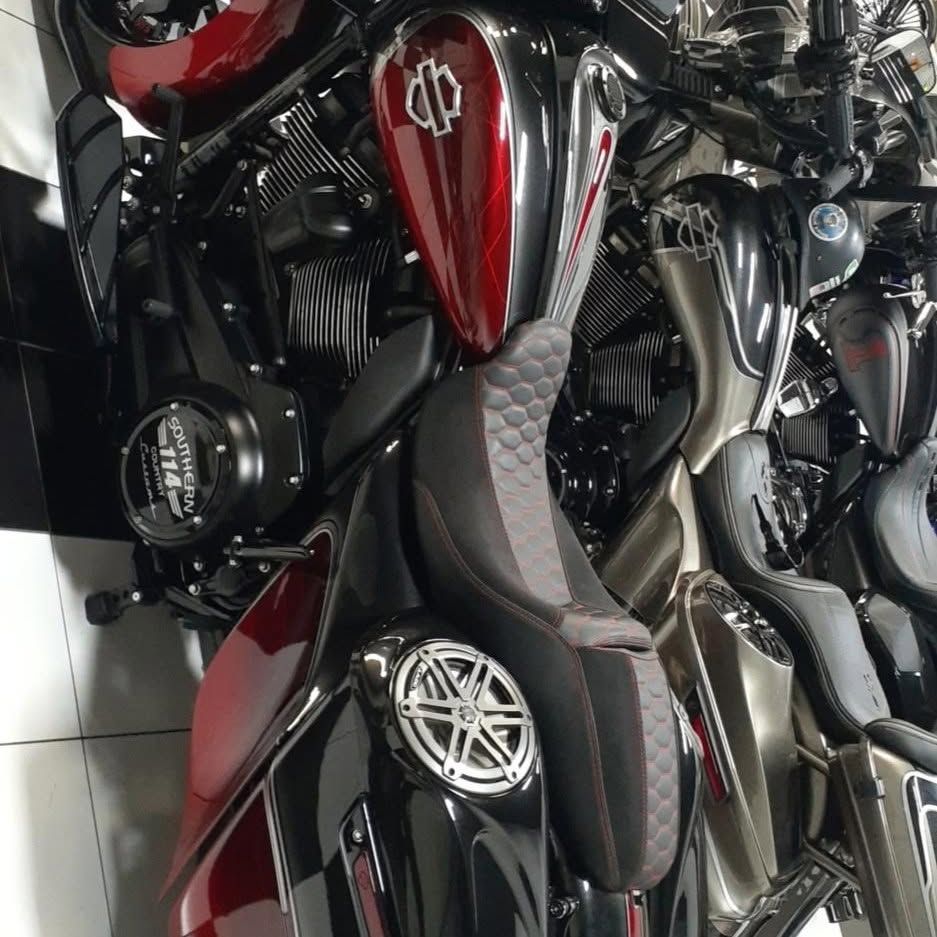 Red and black custom motorcycle with chrome details parked among other bikes indoors