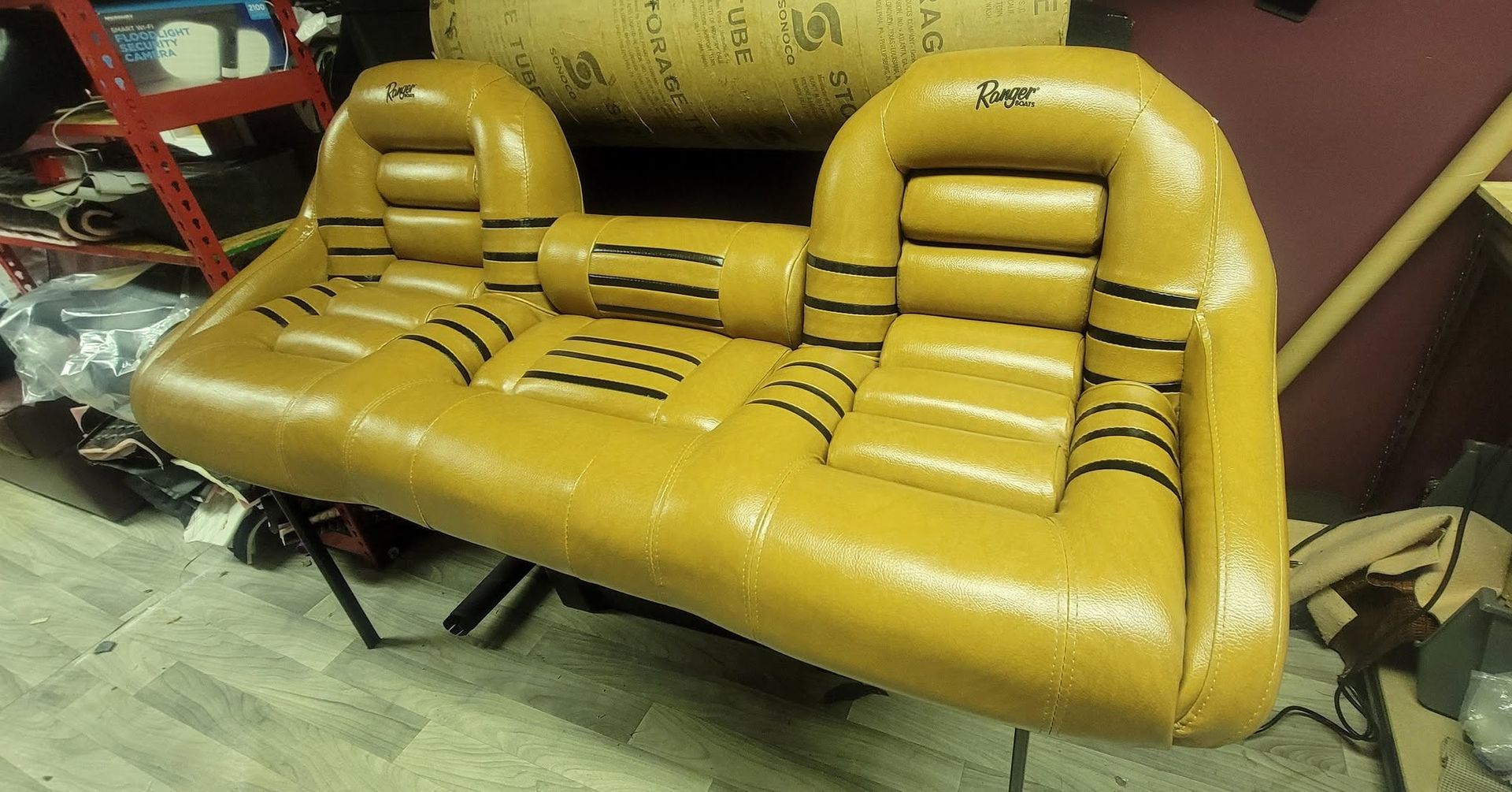 Yellow inflatable two-seat sofa with backrests and armrests in a workshop or storage area