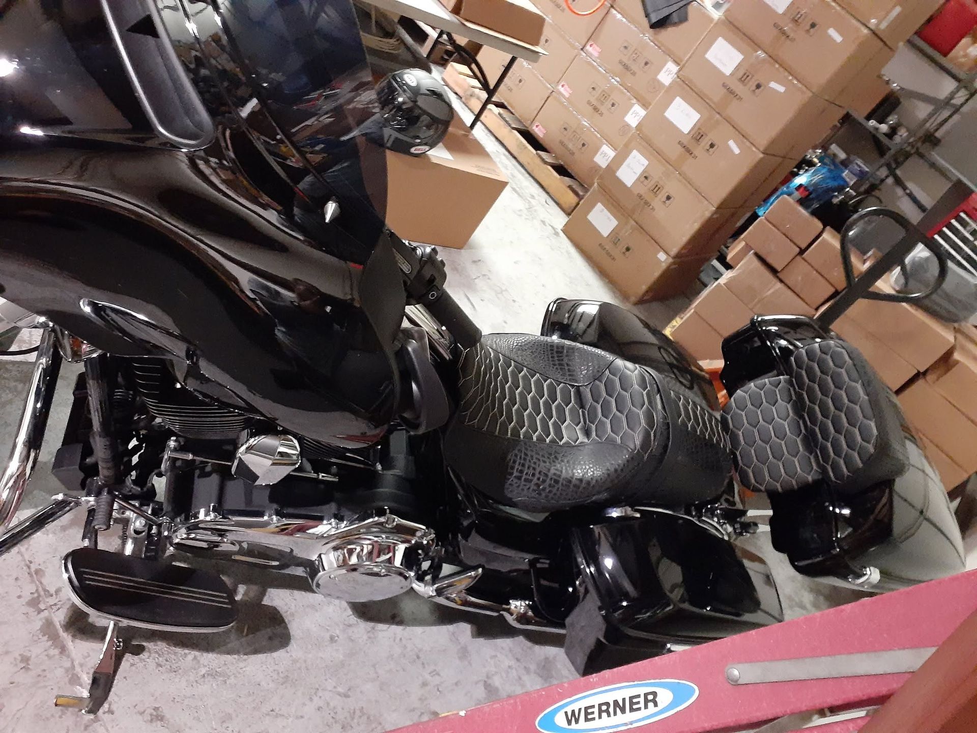 Black motorcycle with chrome details parked in a warehouse beside stacked cardboard boxes