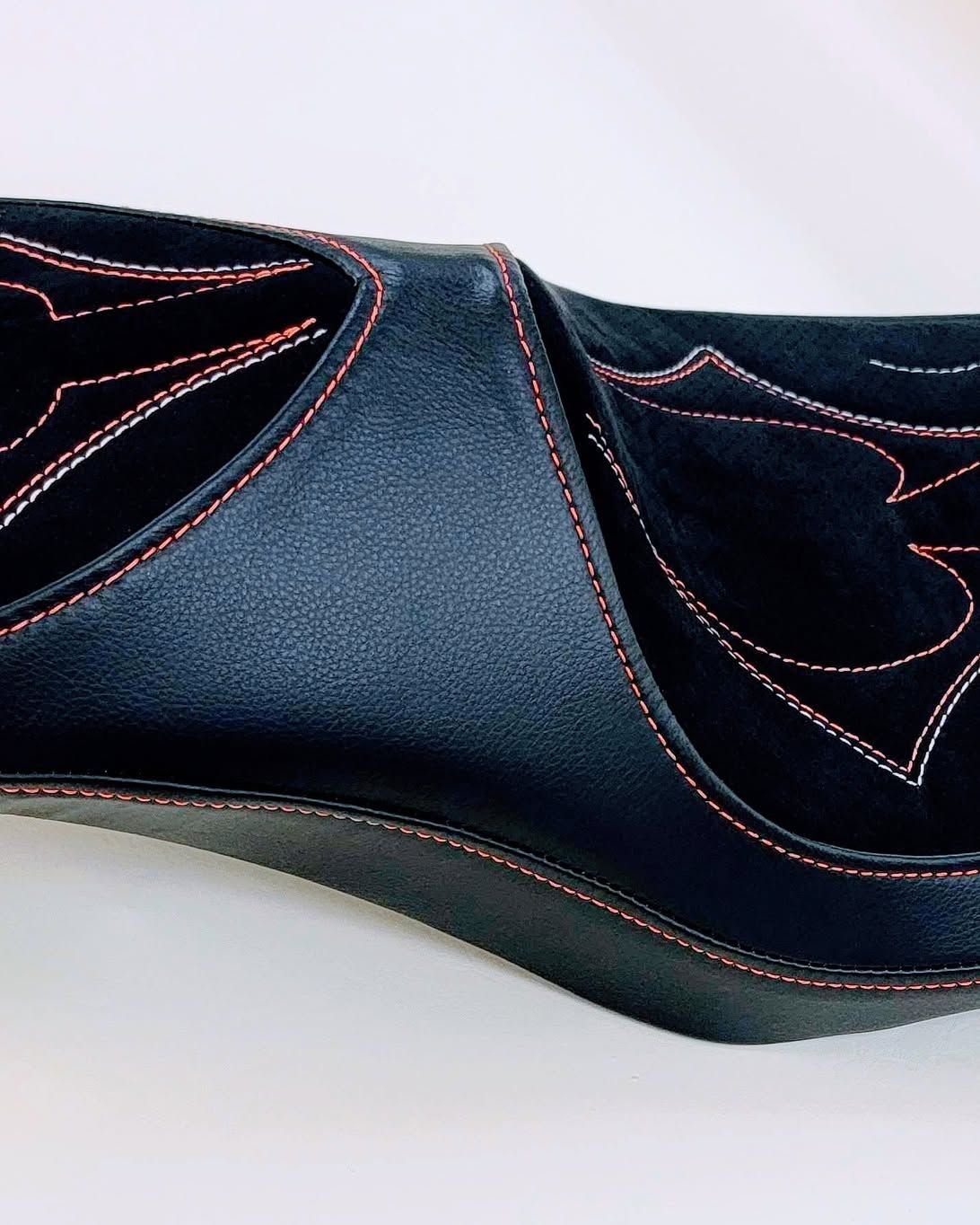 Close-up of a navy and black Western-style boot with pink stitching and a pointed toe