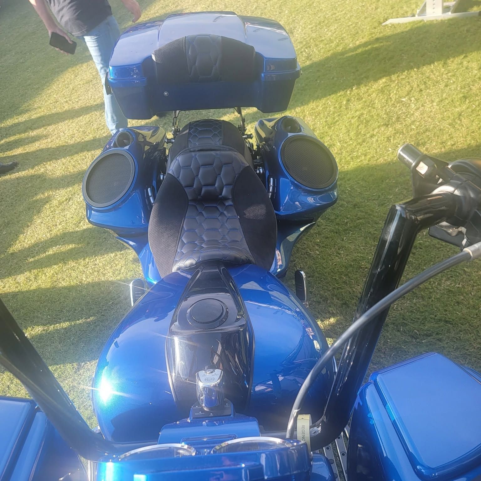 Blue motorcycle seen from above on grass, with a black seat and windshield.