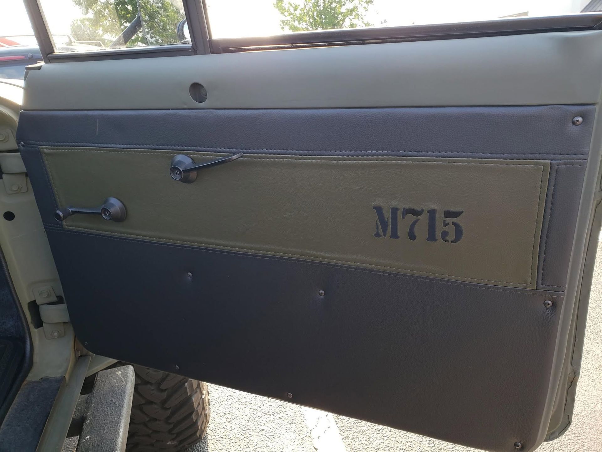 Interior of a vehicle door with olive and black panels and a “M715” marking.