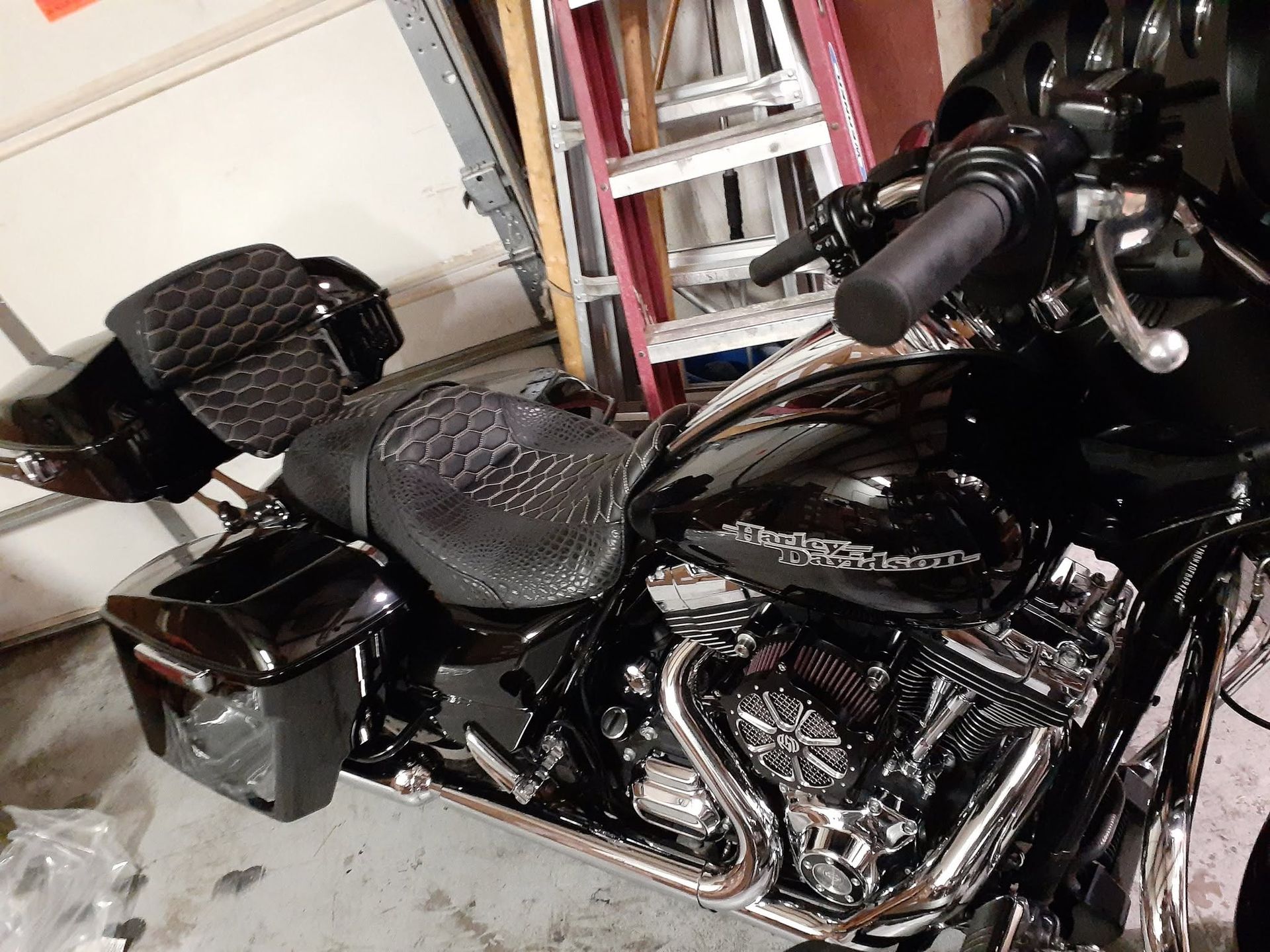 Black motorcycle in a garage with a padded seat, saddlebags, and chrome exhaust