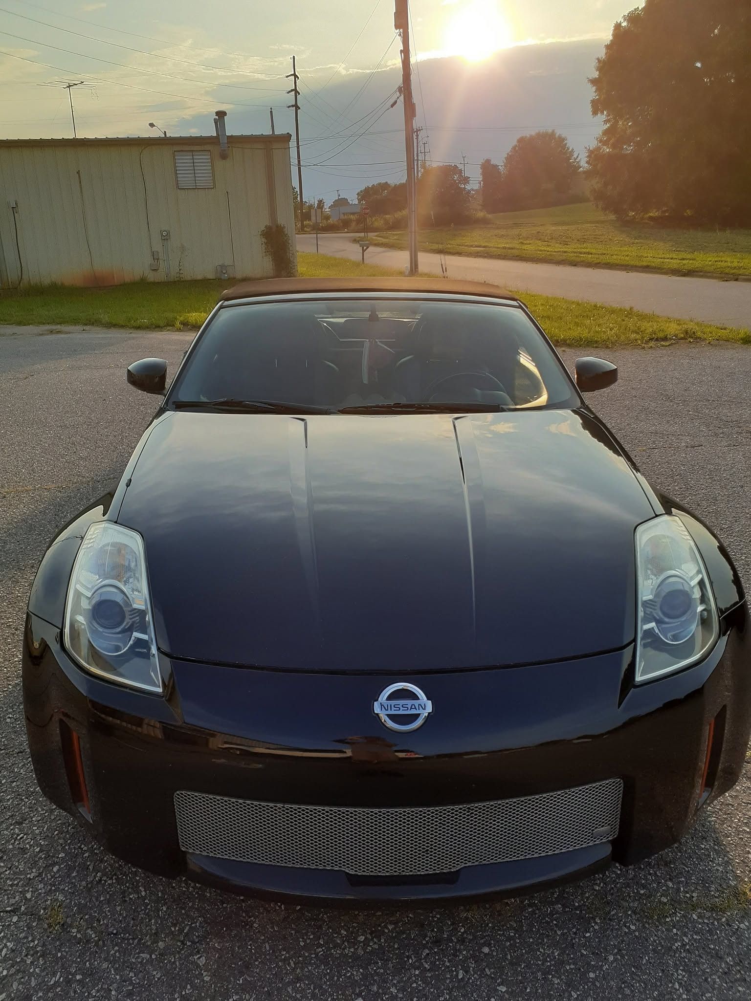 Black Nissan sports car parked on a road at sunset, front view.
