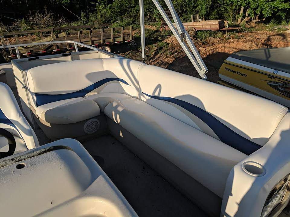 White pontoon boat interior with beige seating and cup holders in a sunny outdoor storage area