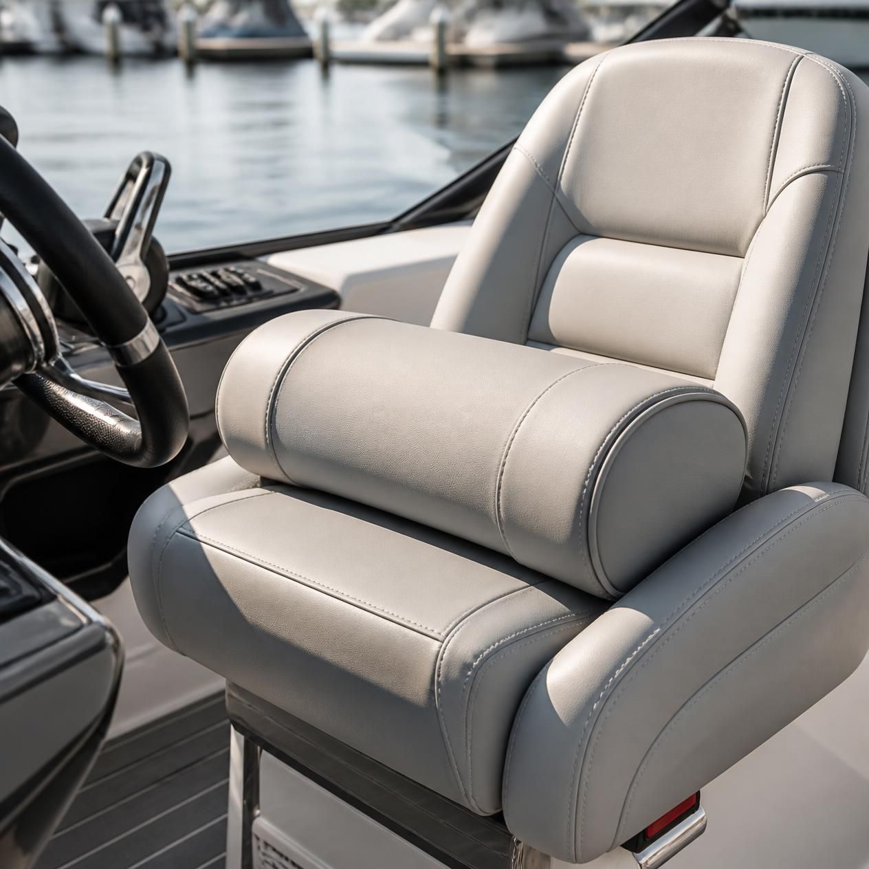 Padded gray boat captain’s chair beside the helm on a docked boat