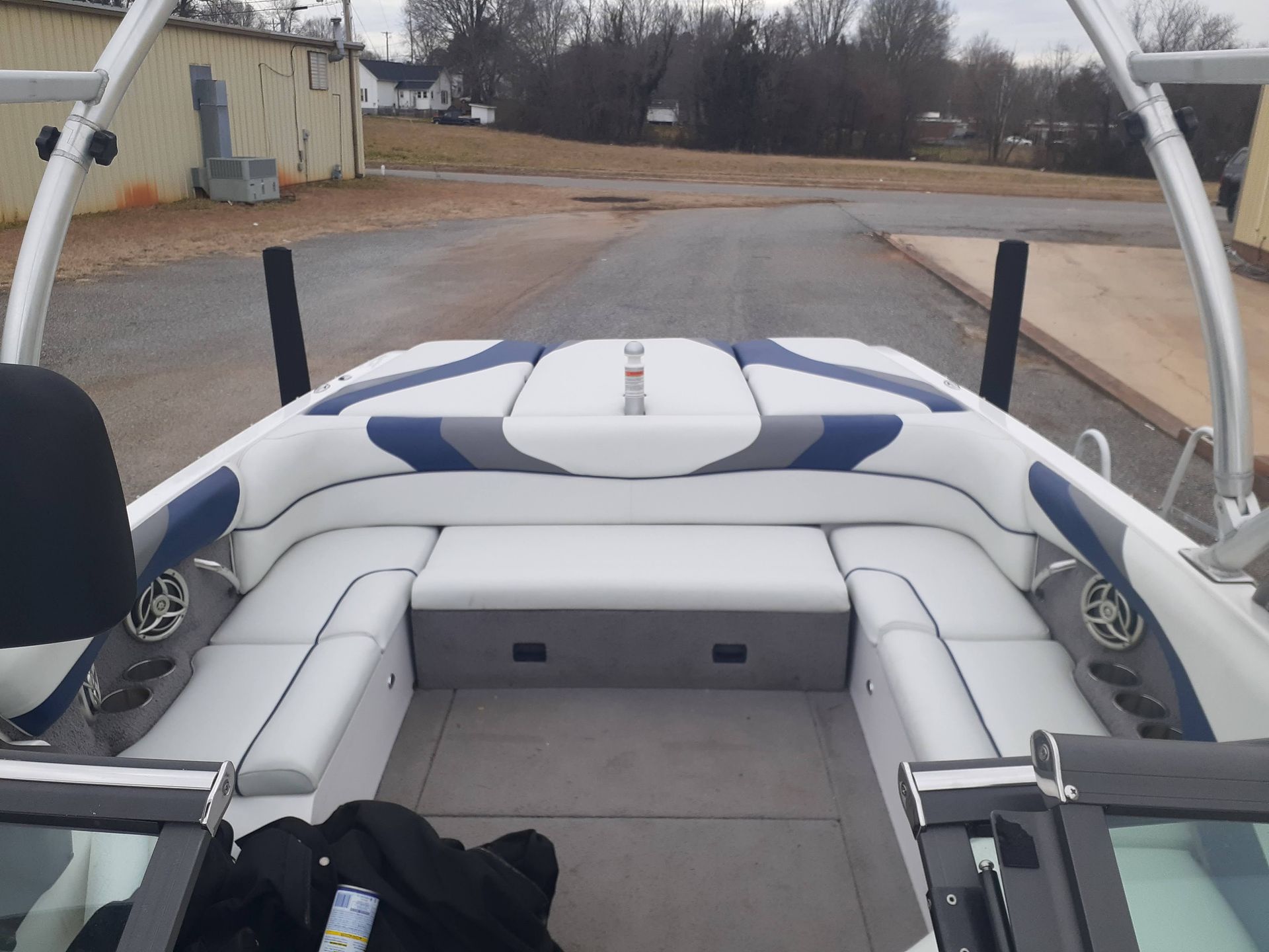 Boat cockpit with white and blue seats facing an open ramp and overcast shore in the distance