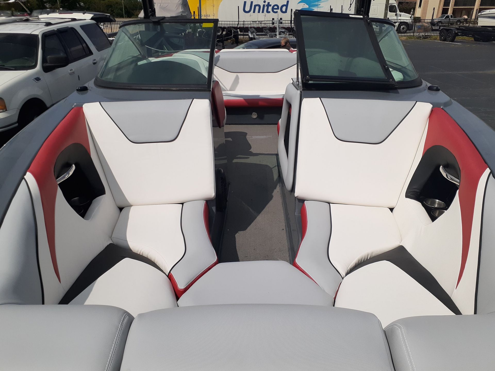 White, red, and gray boat seats and cockpit viewed from the stern in a marina parking lot