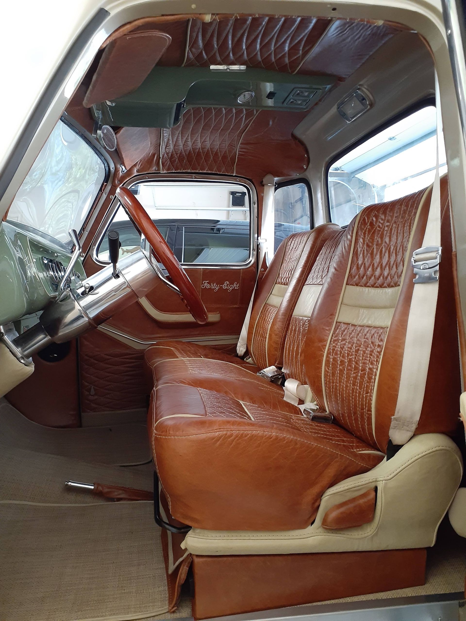 Interior of a vintage van with brown leather seats and wood-paneled trim, viewed from the side door.