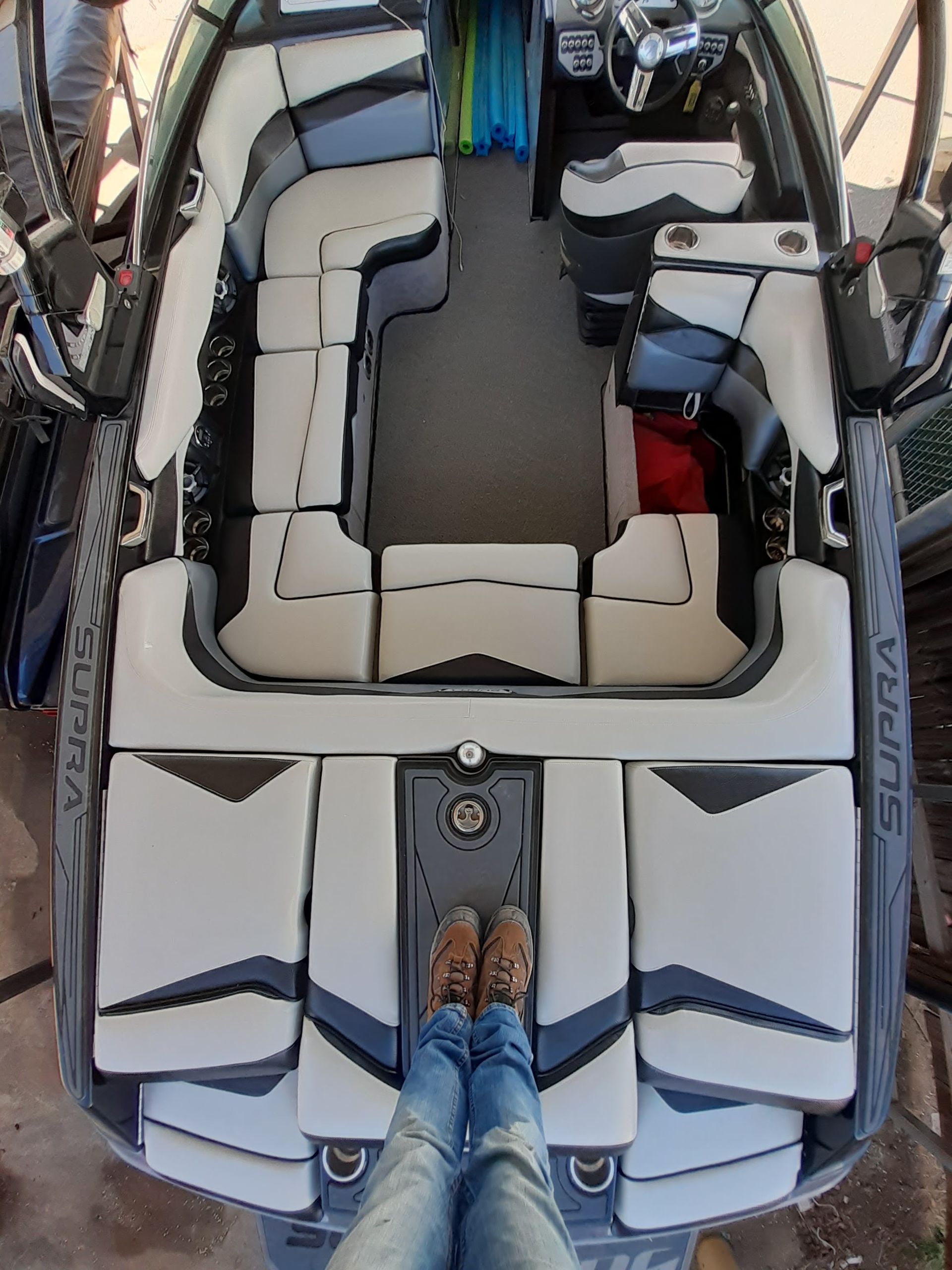 Top-down view of a boat interior with beige seating and a person standing at the stern.