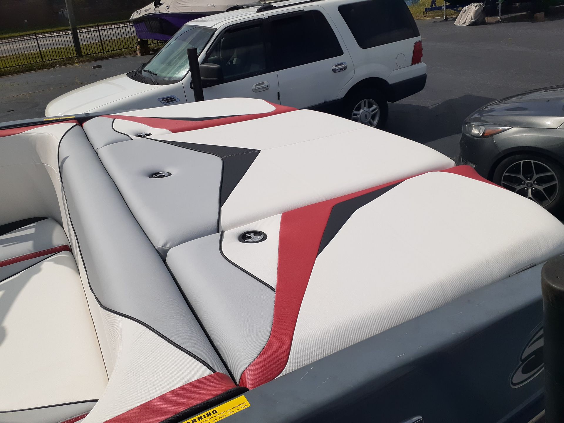White and red boat seats with gray vinyl panels, viewed from above in a parking lot.