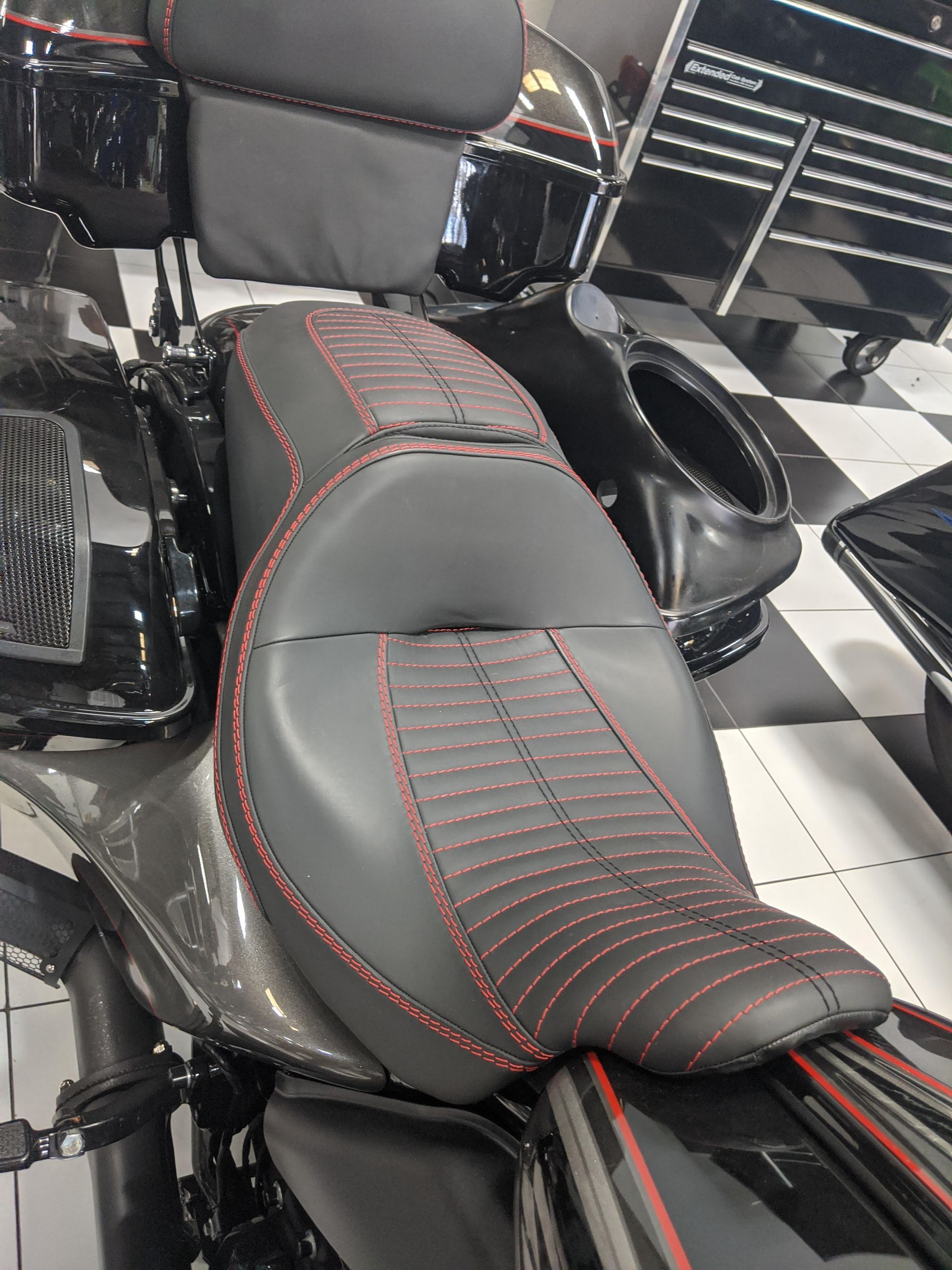 Black motorcycle seat and glossy side panel with a circular speaker-like detail and red reflector