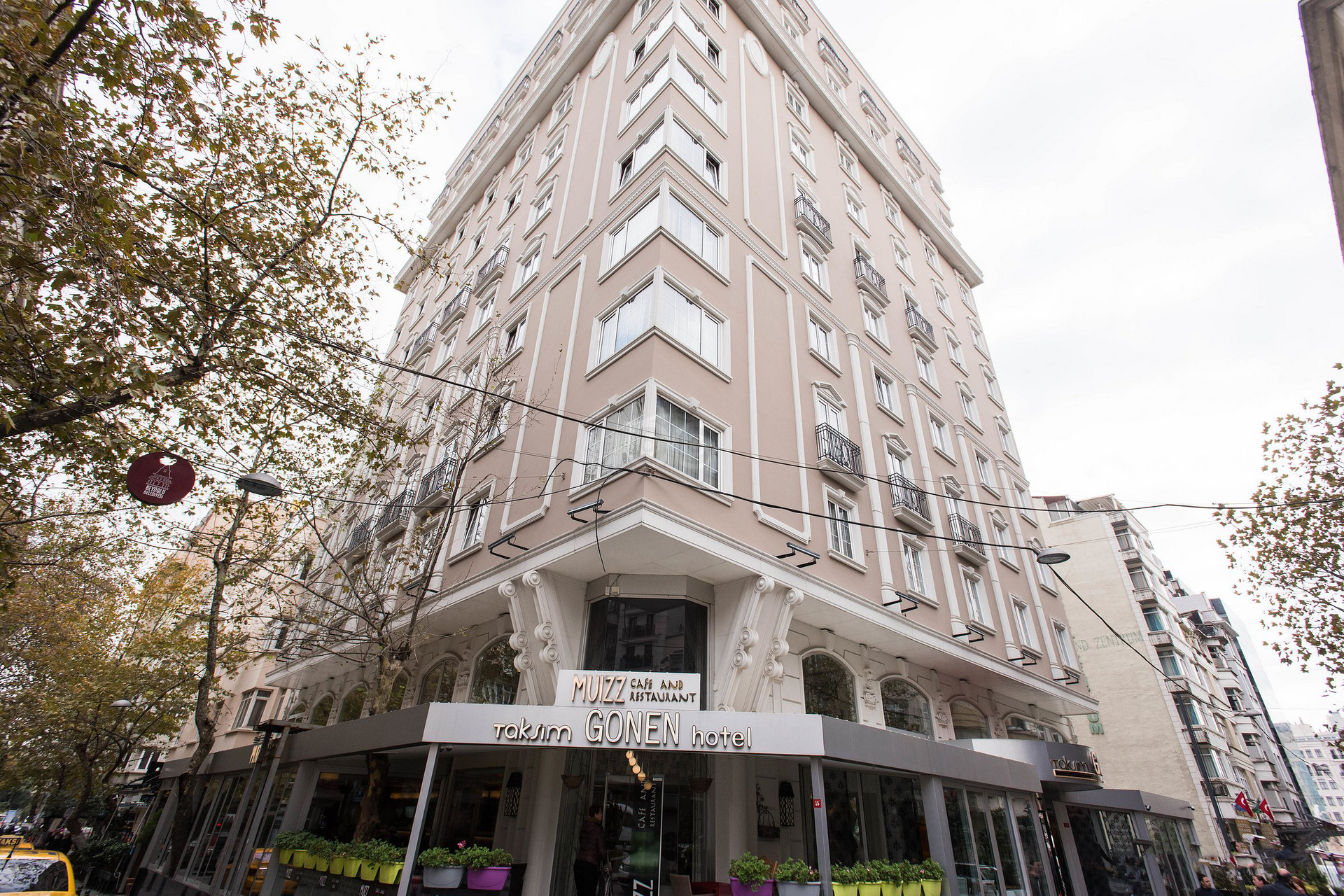A large building with a lot of windows is on the corner of a city street.