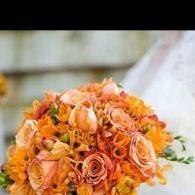 Orange and peach rose bouquet with green leaves, arranged tightly in a round floral arrangement