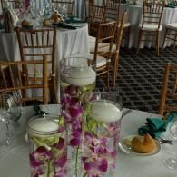 Tall glass floral centerpieces with white lids on a banquet table in a dining room