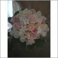 Bouquet of pale pink and white flowers in a dark vase against a wooden background