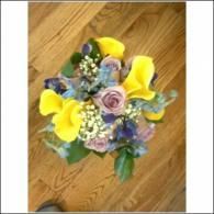 Yellow and purple flower bouquet on a hardwood floor, viewed from above