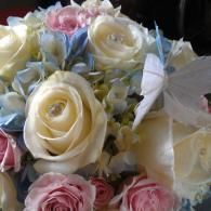Bouquet of cream, pink, and pale blue roses with white decorative feathers