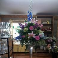 Large floral arrangement with pink lilies and blue accents in a shop interior