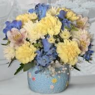 Blue and yellow flower bouquet in a textured blue vase with floral decorations