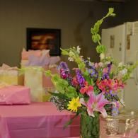 Bouquet of colorful flowers in a glass vase on a pink-covered table at an indoor event