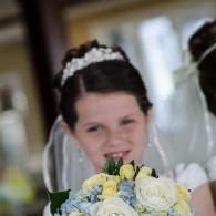 Bride holding a bouquet of white and yellow flowers, smiling in a wedding veil