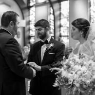 Bride and groom exchanging rings during a wedding ceremony, with officiant beside them