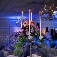 Elegant floral centerpiece with candles in a softly lit banquet hall